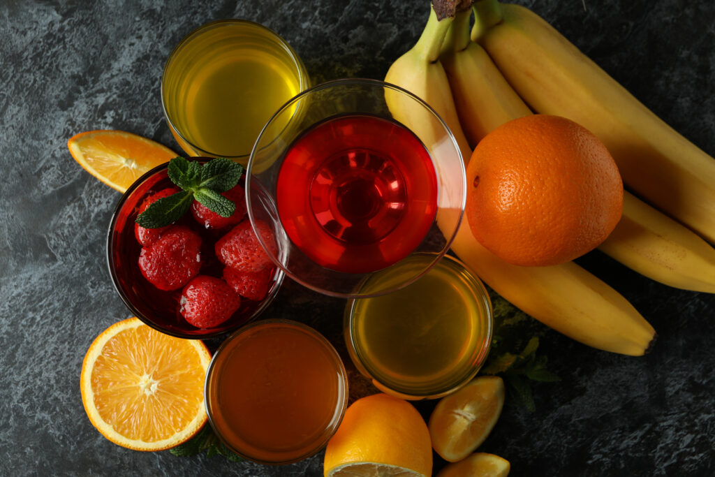 A table topped with fruit and colored water glasses.