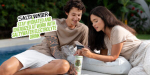 A man and woman relaxing outdoors while staying hydrated and energized with SaltyWater Electrolyte Drink. The text on the image reads 'Stay Hydrated and Energized at Work with SaltyWater Electrolyte Drink'